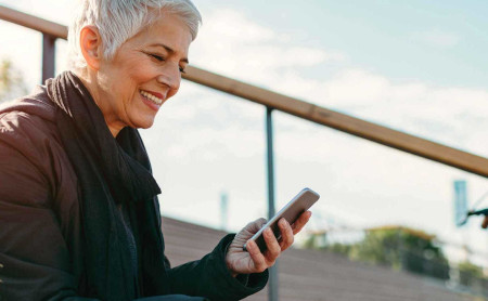 An older woman using her phone while sitting on some steps